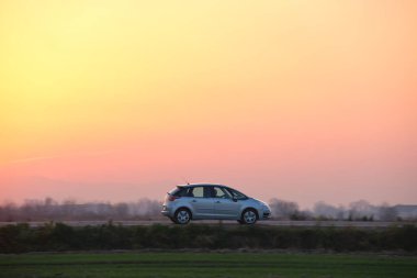 Gün batımında şehir içi yolda hızlı giden bir araba. Akşamları otoyol trafiği.