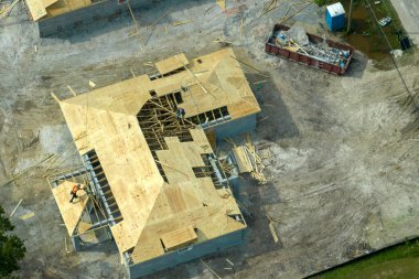 Florida kırsal kesiminde ahşap iskeleti olan bitmemiş bir banliyö evinin çatı inşaatında çalışan profesyonel müteahhitler. Amerika 'da konut geliştirme kavramı.