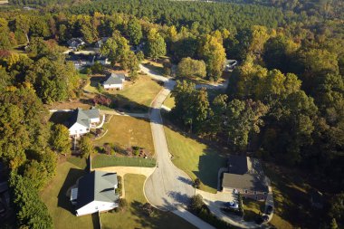 View from above of expensive residential houses between yellow fall trees in suburban area in South Carolina. American dream homes as example of real estate development in US suburbs. clipart