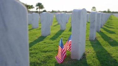 Anma Günü konsepti. Beyaz mezar taşları ve yeşil çimlerin üzerinde Amerikan bayrağı olan Sarasota Ulusal Mezarlığı