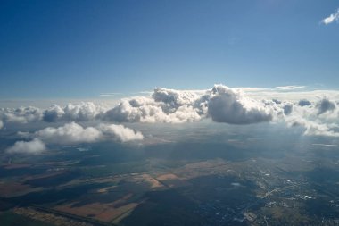 Dünya 'nın yüksek irtifasında, yağmur fırtınasından önce oluşan kabarık kümülüs bulutlarıyla kaplı uçak penceresinden hava görüntüsü.