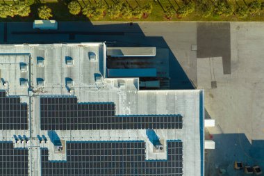 Sanayi binasının çatısına yeşil ekolojik elektrik üretmek için monte edilmiş mavi fotovoltaik panelli güneş enerjisi santralinin hava görüntüsü. Sürdürülebilir enerji konsepti üretimi.