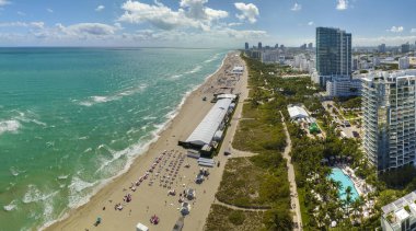 Sıcak Florida güneşinde dinlenen turistlerle birlikte güney sahilinin kumlu yüzeyi. Yüksek lüks otelleri ve apartmanları olan Miami Beach City. Güney Amerika 'da turizm altyapısı.