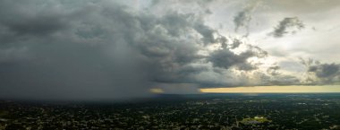 Landscape of dark ominous clouds forming on stormy sky during heavy thunderstorm over rural town area.