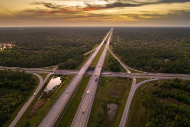 Gün batımında hızlı giden arabalarla Florida, ABD 'de geniş çoklu yol kavşağı. Amerikan ulaşım altyapısının üstü..