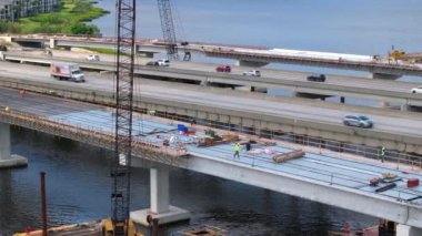 Mavi yakalı işçiler ve otoyolda inşaat halindeki trafik arabaları. Amerikan karayolu üzerinde trafik altyapısı inşa ediliyor