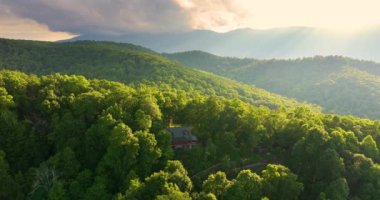 Kuzey Carolina Appalachian dağlarında doğan parlak güneşle aydınlanan dağ gündoğumu ormanındaki ücra bir ev. ABD 'nin seyahat merkezi olarak turizm sığınağı.
