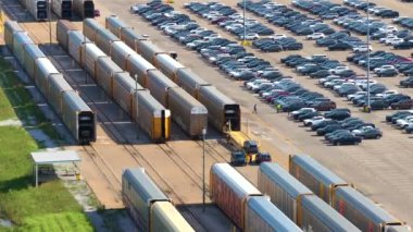 Kargo treni araba taşıyor. Satılık gıcır gıcır arabaları olan bir fabrika otoparkı. Amerikan otomotiv endüstrisinin gelişimi