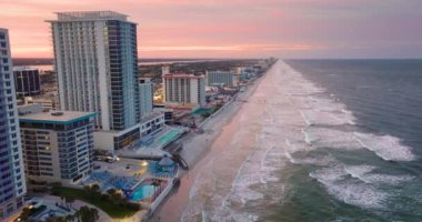 Gün batımında Daytona Plajı 'nda. Lüks otellerin ve apartmanların önündeki kumlu sahilde dalgalar çarpıyor. Güney Florida, ABD 'de turist eğlence altyapısı