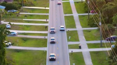 Florida 'daki küçük Amerikan kasabasında kırsal yol trafiği. Yeşil ağaçlar ve sakin yerleşim alanlarındaki banliyö sokakları arasında özel evler var.