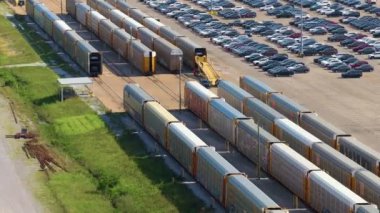 Otomotiv fabrikasının otoparkındaki kargo treni taşıyıcısında yeni arabalar satışa hazır. İthalat ve ihracat için krupiye araç envanteri.
