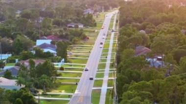 Florida 'daki küçük Amerikan kasabasında trafik arabaları süren kırsal yol. Sakin yerleşim bölgesinde yeşil ağaçlar ve banliyö sokakları arasında özel evler