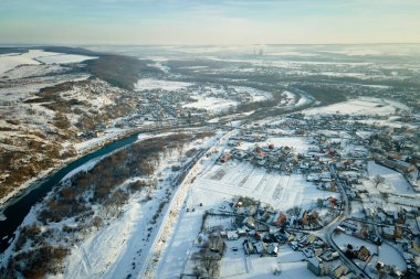 Kışın kırsal kesimde, banliyöde karla kaplı çatıları olan yerleşim yerlerinin hava manzarası..