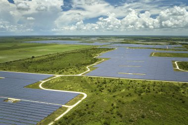 Aerial view of sustainable electric power plant between agricultural farm fields with solar photovoltaic panels for producing clean electrical energy. Renewable electricity with zero emission concept.
