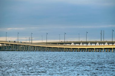 Barron Collier Bridge and Gilchrist Bridge in Florida with moving traffic. Transportation infrastructure in Charlotte County connecting Punta Gorda and Port Charlotte over Peace River. clipart