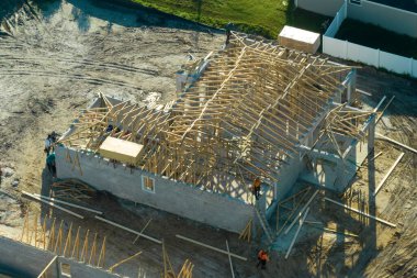 Florida kırsal kesiminde ahşap iskeleti olan bitmemiş bir banliyö evinin çatı inşaatında çalışan profesyonel müteahhitler. Amerika 'da konut geliştirme kavramı.