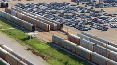 Otomotiv fabrikasındaki sanayi yük treni nakledilmeye hazır yeni arabalarla dolu. Satılık araçları olan otomobil üreticisi otoparkı