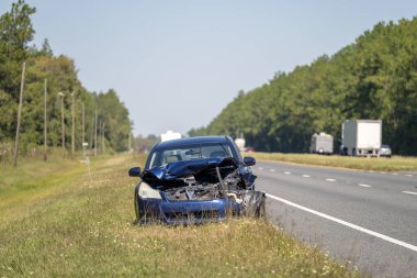 Old crashed car abandoned on highway road shoulder. Damaged in traffic accident vehicle parked on roadside. clipart