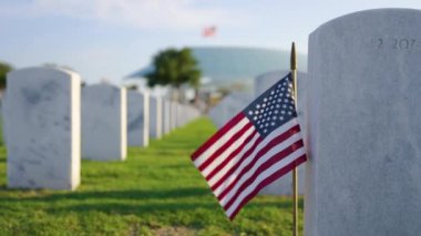 Anma Günü konsepti. Beyaz mezar taşları ve yeşil çimlerin üzerinde Amerikan bayrağı olan Sarasota Ulusal Mezarlığı