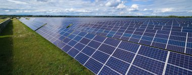 Temiz elektrik enerjisi üretmek için sıra sıra güneş fotovoltaik panelleri olan sürdürülebilir büyük elektrik santralinin havadan görünüşü. Sıfır emisyonlu yenilenebilir elektrik kavramı.