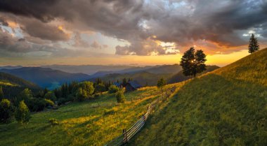 Dağ yamacındaki çoban evleri ve batan güneşle aydınlatılmış çam ormanları. Vahşi dağlarda renkli günbatımının havadan görünüşü. Güzel doğa manzarası.