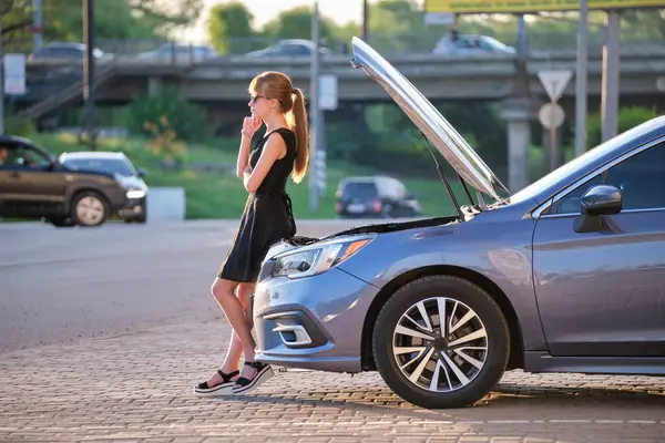 Kaputu ve bozuk motoruyla şehir sokağında duran üzgün kadın şoför yol yardımının gelmesini bekliyor..