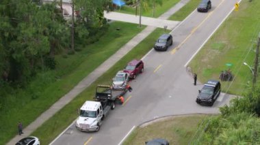 Tow truck loading crashed car on accident site. Emergency services personnel and vehicles responding to vehicle crash on American street. First responders helping on road in the USA