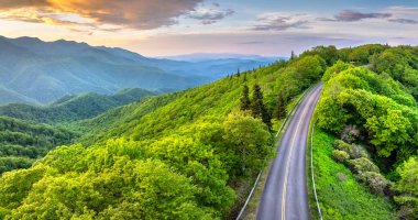 Gün batımında Tennessee Appalachian dağlarında araba sürmek. Yaz mevsiminde yeşil tepe örtüleriyle dağ ormanlarında dolambaçlı bir yol..
