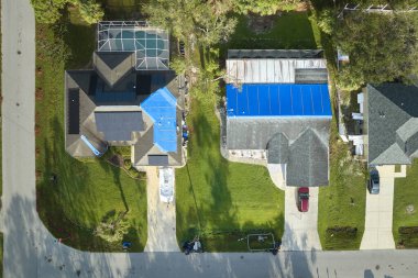 Asfalt kiremitlerin yerine konana kadar yağmur suyu sızıntılarına karşı koruyucu branda örtüleriyle kaplı çatı sızdıran evin üst görüntüsü. Florida 'daki Ian Kasırgası' nın yol açtığı çatı hasarı.