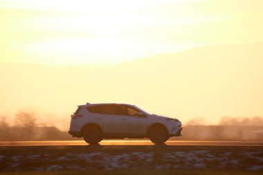 Gün batımında şehirlerarası yolda hızla giden bir SUV arabası. Akşamları otoyol trafiği.
