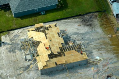 Florida 'nın banliyö bölgesinde ahşap iskeleti olan bitmemiş bir konutun çatı inşaatında çalışan inşaatçılar. Konut geliştirme kavramı.