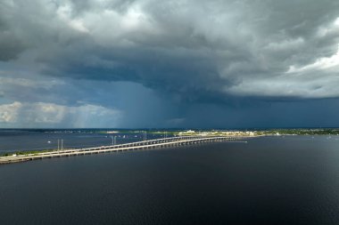 Stormy clouds forming from evaporating humidity of ocean water before thunderstorm over traffic bridge connecting Punta Gorda and Port Charlotte over Peace River. Bad weather conditions for driving.