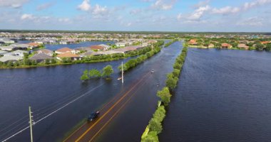Sürücü aracıyla dolu bir cadde ve Florida yerleşim bölgesinde su evleri ile çevrili. Kasırga doğal felaketinin sonuçları.
