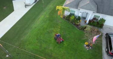 Florida banliyösünün arka bahçesinde çim biçme makinesi ile çim biçen profesyonel bir servis işçisi.