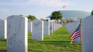 Amerikan ordusu Sarasota Ulusal Mezarlığı 'nda beyaz mezar taşları ve Amerikan bayrağı yeşil çimlerde. Anma Günü konsepti.