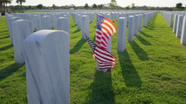 Amerikan ordusu Sarasota Ulusal Mezarlığı 'nda beyaz mezar taşları ve Amerikan bayrağı yeşil çimlerde. Anma Günü konsepti.