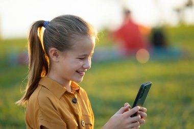 Yaz parkında bir arkadaşıyla cep telefonuyla oyun oynayan pozitif çocuk..