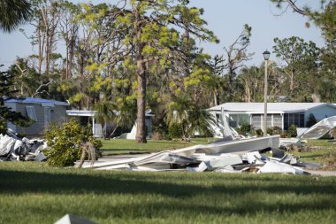 Kasırganın yol kenarındaki metal çöpler Florida yerleşim bölgesindeki evlere ağır hasar vermiş. Doğal afetten sonra.
