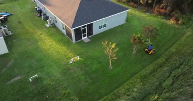 Sıfır dönüşlü çim biçme makinesi kullanan adam yazın Florida 'daki ev bahçesinde çim biçiyor.