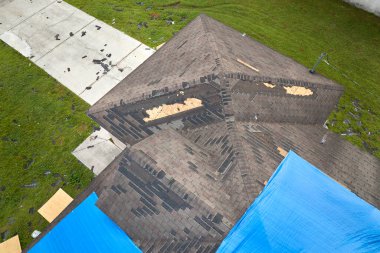 Asfalt kiremitlerin yerine konana kadar yağmur suyu sızıntılarına karşı koruyucu branda örtüleriyle kaplı çatı sızdırma manzarası. Florida 'daki Ian Kasırgası' nın yol açtığı çatı hasarı.