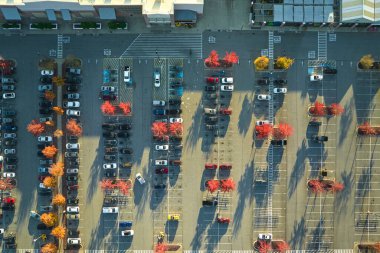 Rgocery mağazasının önündeki büyük otoparkın havadan görüntüsü. Bir sürü renkli araba park edilmiş. Araç mekanları ve yönleri için çizgiler ve işaretlerle süpermerkez alışveriş merkezindeki otopark..