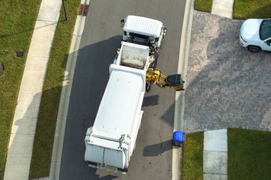 Çöp kamyonu Amerikan mahallesinin kaldırımından çöp kutusu yüklüyor..