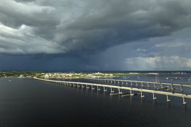 Stormy clouds forming from evaporating humidity of ocean water before thunderstorm over traffic bridge connecting Punta Gorda and Port Charlotte over Peace River. Bad weather conditions for driving.