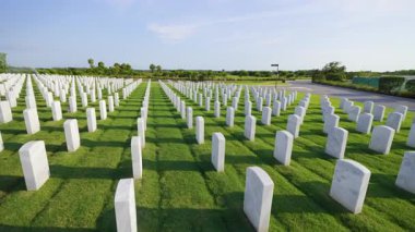Sarasota Ulusal Mezarlığı 'nda yeşil çimlerin üzerinde bir sürü beyaz mezar taşı var. Anma Günü konsepti