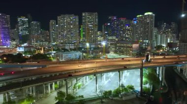Gece yarısı Miami, Florida 'da hızlı sürüş yapan arabalarla kavşağın üzerinde gökdelen binaları olan Amerikan kentsel manzarası