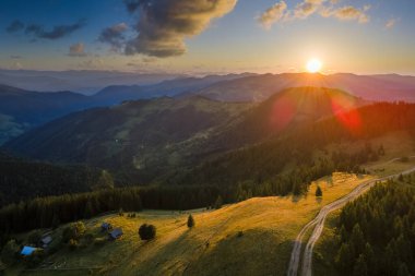 Yamaçta eski çoban evi olan vahşi dağ ormanlarında gün batımı manzarası inanılmaz. Parlak batan güneşle aydınlatılmış karanlık çam ağaçları. Güzel doğa manzarası.