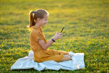 Cep telefonuyla oyun oynayan mutlu çocuk portresi.