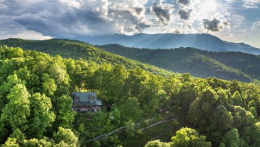 ABD seyahat rotası. Mount Mitchell ve Kuzey Carolina Appalachian dağlarında doğan parlak güneşle aydınlanan dağ gündoğumu ormanındaki ücra bir ev. Yamaçtaki turist barınağı.