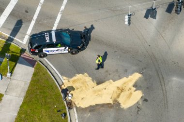 Hurdacı işçiler araba kazasından sonra yol yüzeyini temizliyor. Trafik kazasının olduğu yerde kum emme yağı dökülmüş..