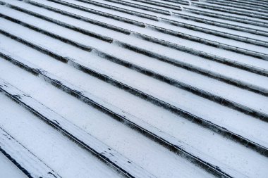 Aerial view of sustainable electrical power plant with solar photovoltaic panels covered with snow in winter for producing clean energy. Concept of low effectivity of renewable electricity in north.